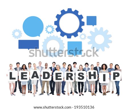 Multi-Ethnic Group Of Business And Casual People Holding Letters That Form Leadership With Speech Bubbles And Gears Above