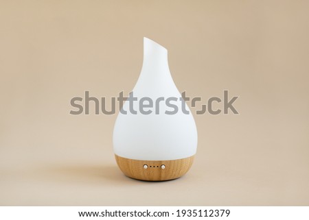 White and wood essential oil diffuser on tan background Royalty-Free Stock Photo #1935112379