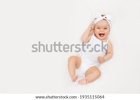 smiling newborn baby on a white bed at home, the concept of a happy, healthy baby, a place for text Royalty-Free Stock Photo #1935115064
