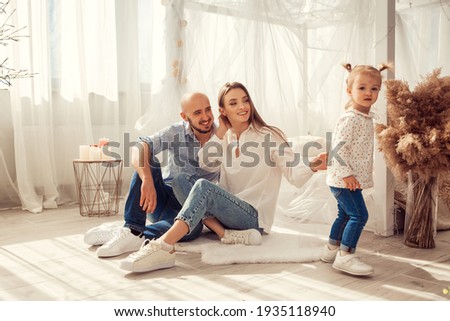 Young family at home in ltgh bedroom with thier daughter