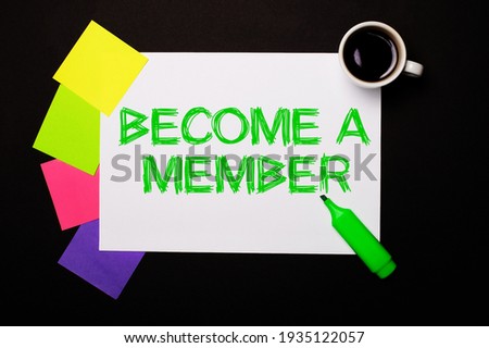 A sheet of paper with the words BECOME A MEMBER, a cup of coffee, bright multi-colored stickers for notes and a green marker on a black background. View from above.