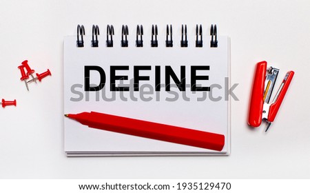 On a light background, a red pen, a red stapler, red paper clips and a notebook with the inscription DEFINE