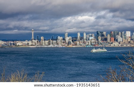 A ferry moves across Elliott Bay in front of skyscrapers in Seattle, Washington. Royalty-Free Stock Photo #1935143651