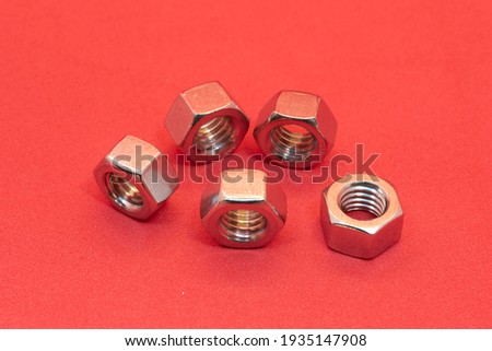 Five metal nuts in a red background