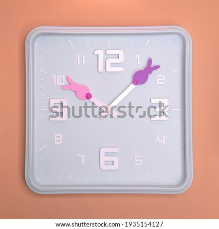 it is easter time. Blue clock with bunny on hands. Simple flat lay easter concept