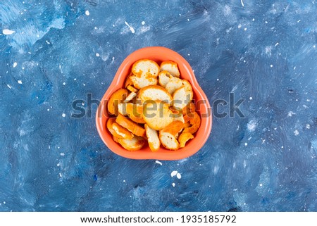 On blue background, toasted bread in vintage orange bowl. High quality photo
