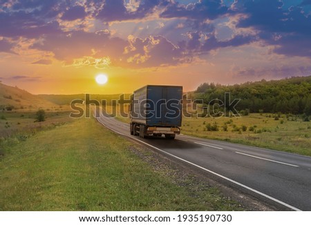 Truck moves along a suburban highway at sunset in summer. Royalty-Free Stock Photo #1935190730