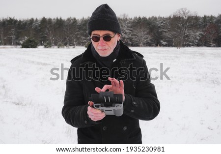 smart man checking the remote button for play drone in winter time 