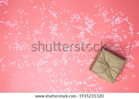 Gift box with brown Kraft paper surrounded with pink daisies and flatlay pink background, spring, Happy Mothers Day, Valentines Day and other Holliday concept top view, Modern design copy space