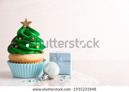 Christmas tree shaped cupcake and decor on table. Space for text