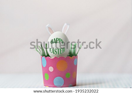 White chicken egg with bunny ears in an eco-friendly pink paper tray, box. Happy Easter holiday concept. English text Happy Easter .