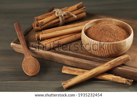 Aromatic cinnamon sticks and powder on wooden table Royalty-Free Stock Photo #1935232454