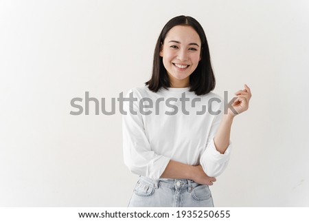 Smiling, beautiful brunette posing on a white wall. Young woman is standing at blank wall.