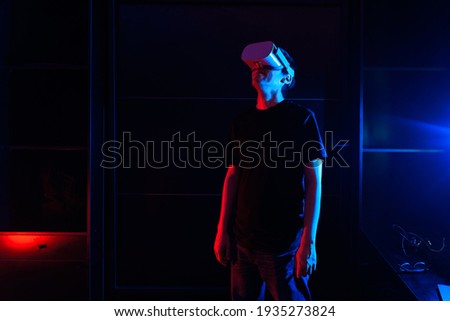 Gamer boy using virtual reality glasses having fun at home with cool lights.