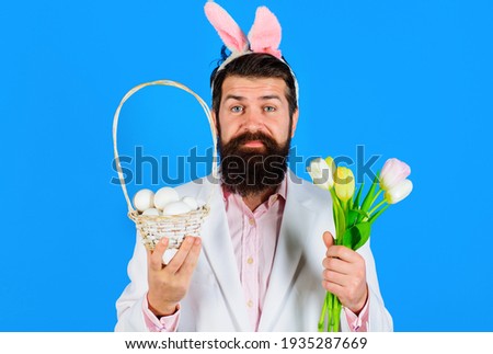 Easter holidays. Bearded man in suit with basket egg. Male with basket eggs and bouquet of tulips.