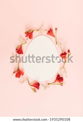 Easter theme with red and white flowers and empty space in the shape of an egg. Minimal spring composition with pastel pink background.