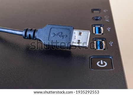 USB cable near two ports on the top of a modern computer tower case. Information transfer and storage device. Universal Serial Bus standard for PC cables and connectors. Closeup. 