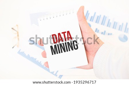 Businessman holding a white notepad with text DATA MINING , business concept