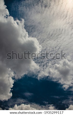 portrait image of a white cumulus cloud floating gently over a blue sky covered by white Altocumulus clouds.