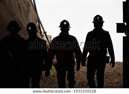 Silhouette of miners with headlamps entering a mine Royalty-Free Stock Photo #1935310528