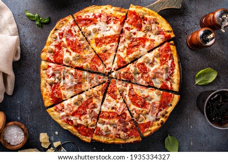 Meat lover pizza with pepperoni, ham and sausage, whole sliced pie Royalty-Free Stock Photo #1935334327