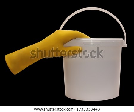 white bucket, yellow glove, the isolated black background, the instrument of isolation a feather.