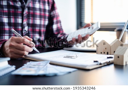 Asian businessman holding a pen to sign a contract to buy or sell a house and land, a contract signing idea.