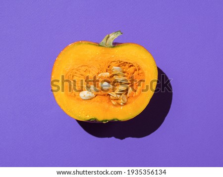Half of a large ripe pumpkin on a purple background. A delicious and healthy vegetable.