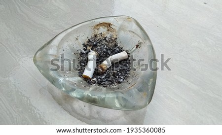a glass ashtray with two cigarette end