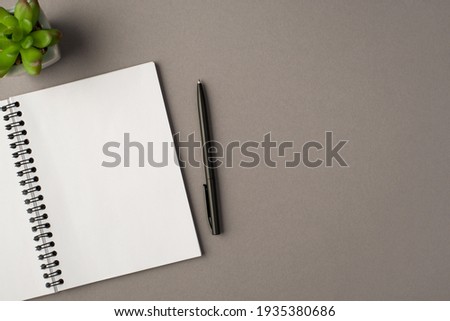 Above photo of notebook green plant and black pen isolated on the grey background with empty space Royalty-Free Stock Photo #1935380686