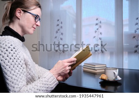 Woman in glasses reading book at home