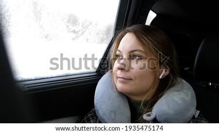 Young beautiful woman listening music in headphones sitting in backseat in car. 3840x2160