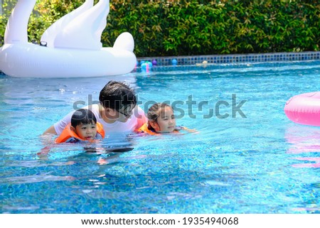happy asia single dad with son and daughter playing in swimming pool Royalty-Free Stock Photo #1935494068