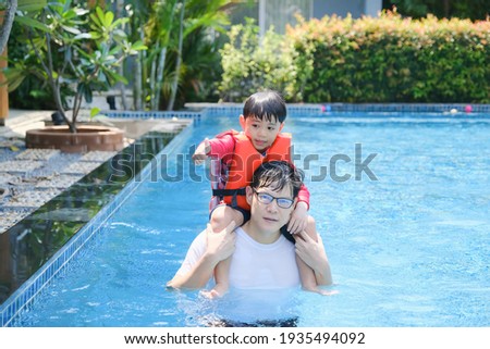 happy asian single dad with son playing in swimming pool