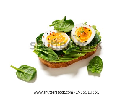 Healthy toast with sliced avocado, boiled eggs, spices and fresh spinach. Delicious breakfast or snack isolated on white background Royalty-Free Stock Photo #1935510361