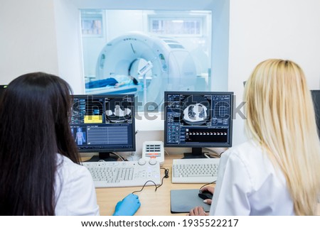 Radiologist and assistant in the control room of computed tomography at hospital Royalty-Free Stock Photo #1935522217
