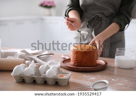 Young woman with traditional Easter cake in kitchen, closeup. Space for text