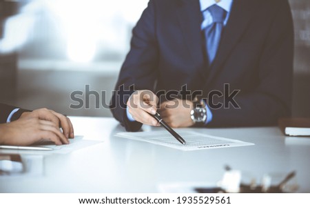 Business people, discussing a contract, working together at meeting, sitting at the desk in a modern office. Unknown businessman with a colleague, lawyers at negotiation. Teamwork and partnership