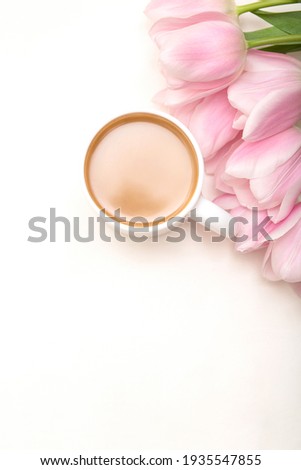 Coffee mug with pink tulip flowers on white table top view, happy morning concept, copy space