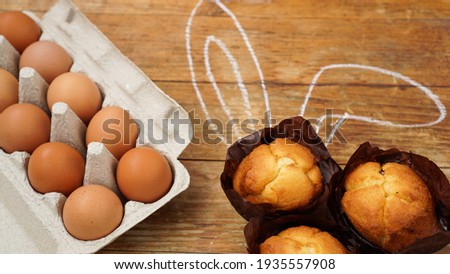 Homemade muffin with painted rabbit ears. Muffin and eggs on a wooden background. Easter dessert concept