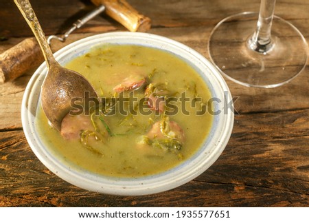 green broth with pepperoni and cabbage top view on rustic wooden table with selective focus glass of oil and pepper grinder
