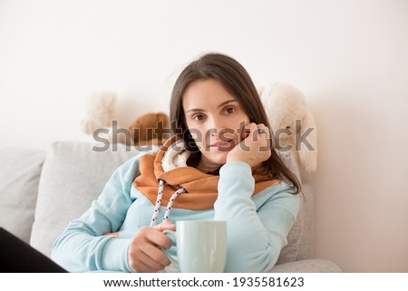 Tired mother, sitting on the couch with a cup of coffee after sleepless night with newborn child