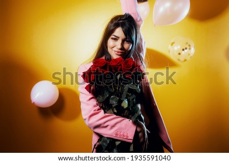 Portrait of young girl with black  hair in party outfit and ballons smiling isolated on yellow background celebrating his birthday. Birthday holiday party concept.