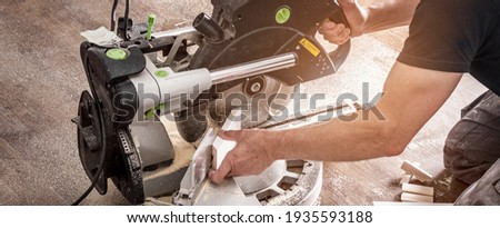 Saw the skirting board on the large circular saw at a 45 degree angle Royalty-Free Stock Photo #1935593188