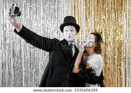 Mime artists, lady poses at gentleman with camera