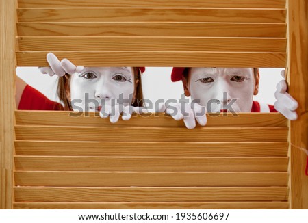 Two mime artists look through wooden partition