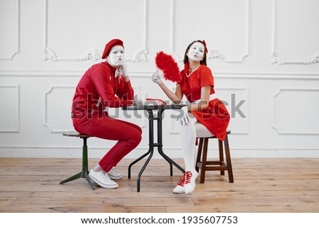 Mime artists in red costumes, scene at the table