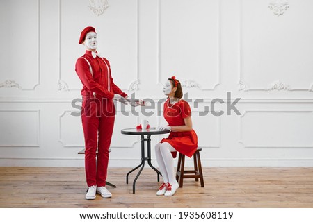 Two mime artists in red costumes, scene with gift