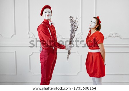 Mime artists in red costumes, scene with bouquet