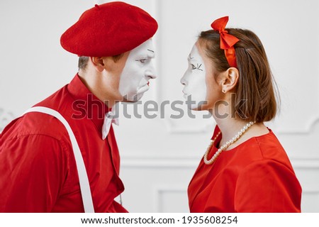 Mime artists in red costumes look at each other
